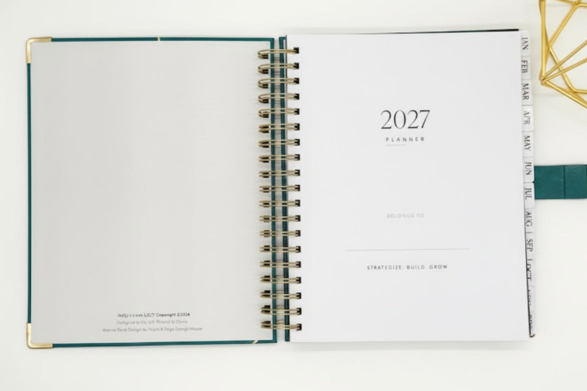 2027 Planner open to  "this planner belongs to" page, with tabbed months, coil binding, and styled alongside a gold geometric decor.