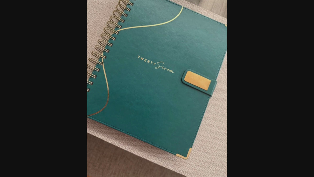 2027 Planner product showcase video with voiceover and on-screen text, featuring photos of the planner, teal bookmark, exterior and interior spreads, and a person in a white long sleeve blazer holding the planner.  