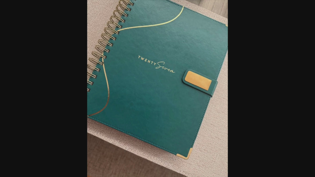 2027 Planner product showcase video with voiceover and on-screen text, featuring photos of the planner, teal bookmark, exterior and interior spreads, and a person in a white long sleeve blazer holding the planner.  