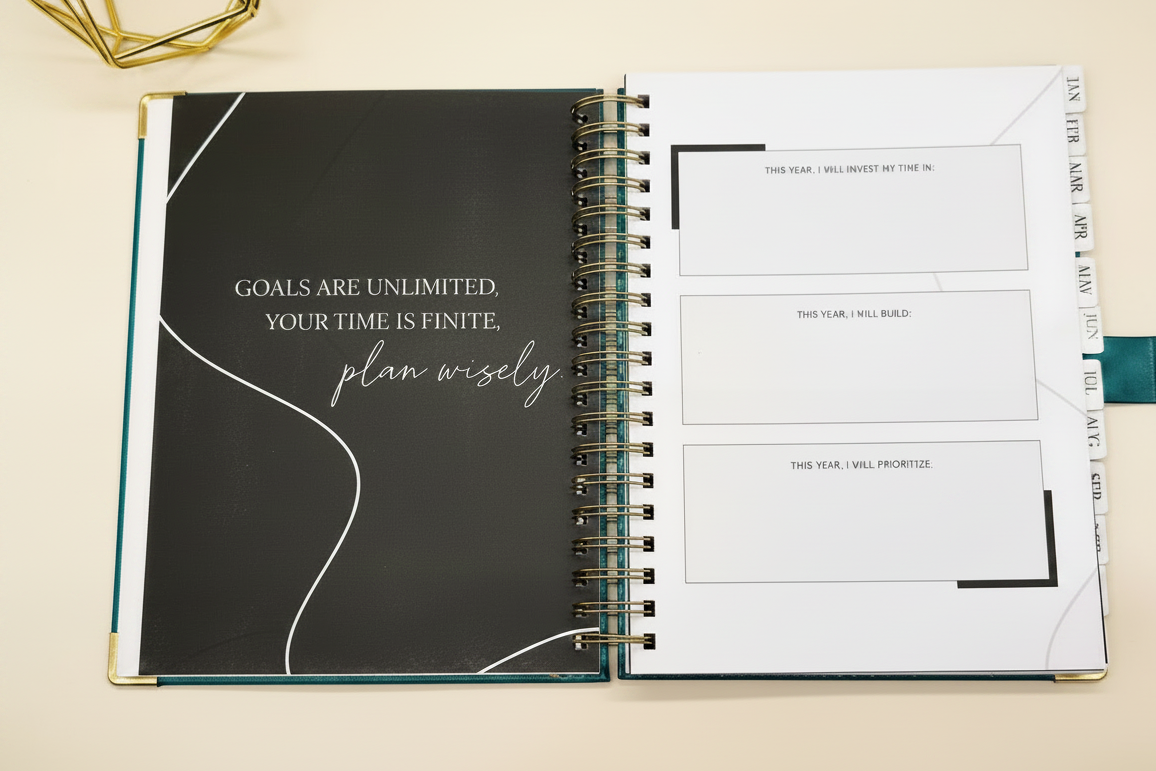 2027 Planner open to  the goal setting page, with tabbed months, coil binding, and styled alongside a gold geometric decor.