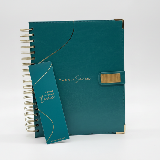 2027 teal planner with teal bookmark that is closed and upright, showcasing coil binding, reinforced corners and gold accent closure.